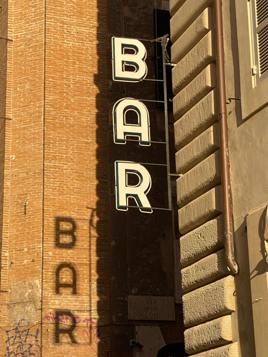 The insegna for a bar in Rome with the shadow behind it