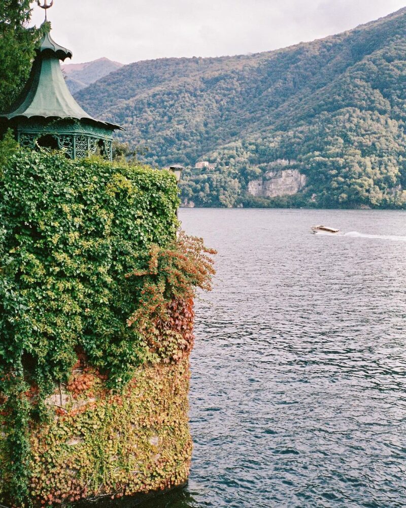 A beautiful view of lake como with a jut out and ivy growing
