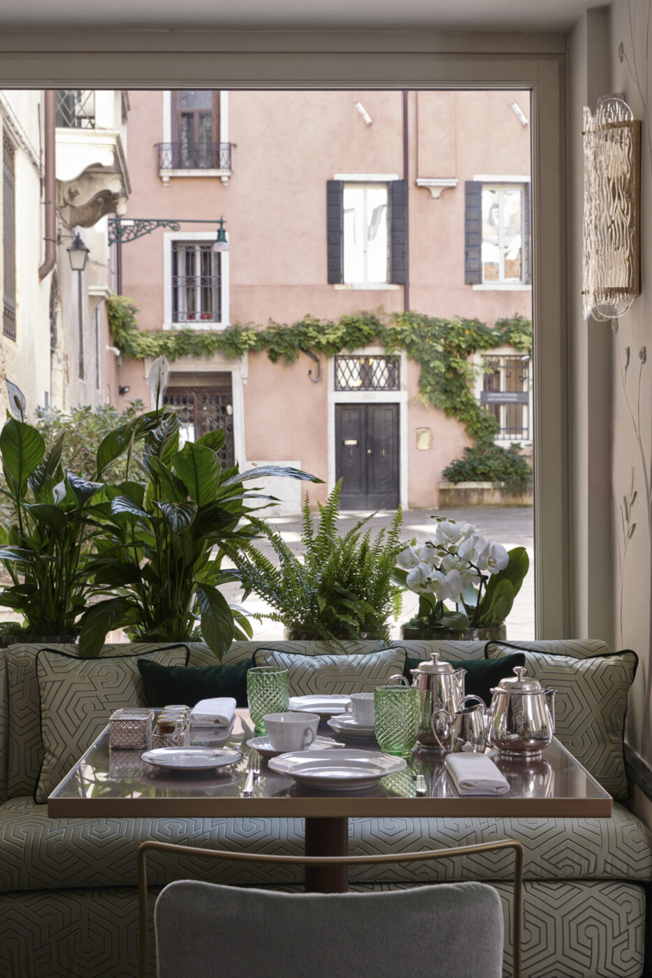 a breakfast table against the window and a light green love seat