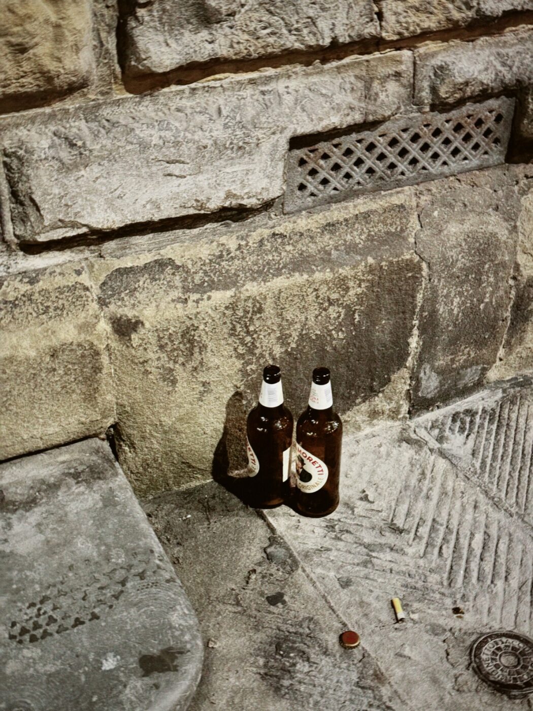 two empty peroni bottles sitting on the ground after a night out