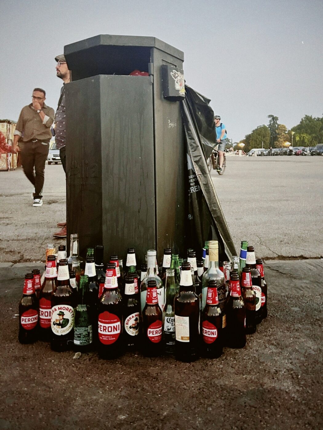 a photo of a ton of empty beer bottles piled up next to the trash can on Piazzale Michelangelo