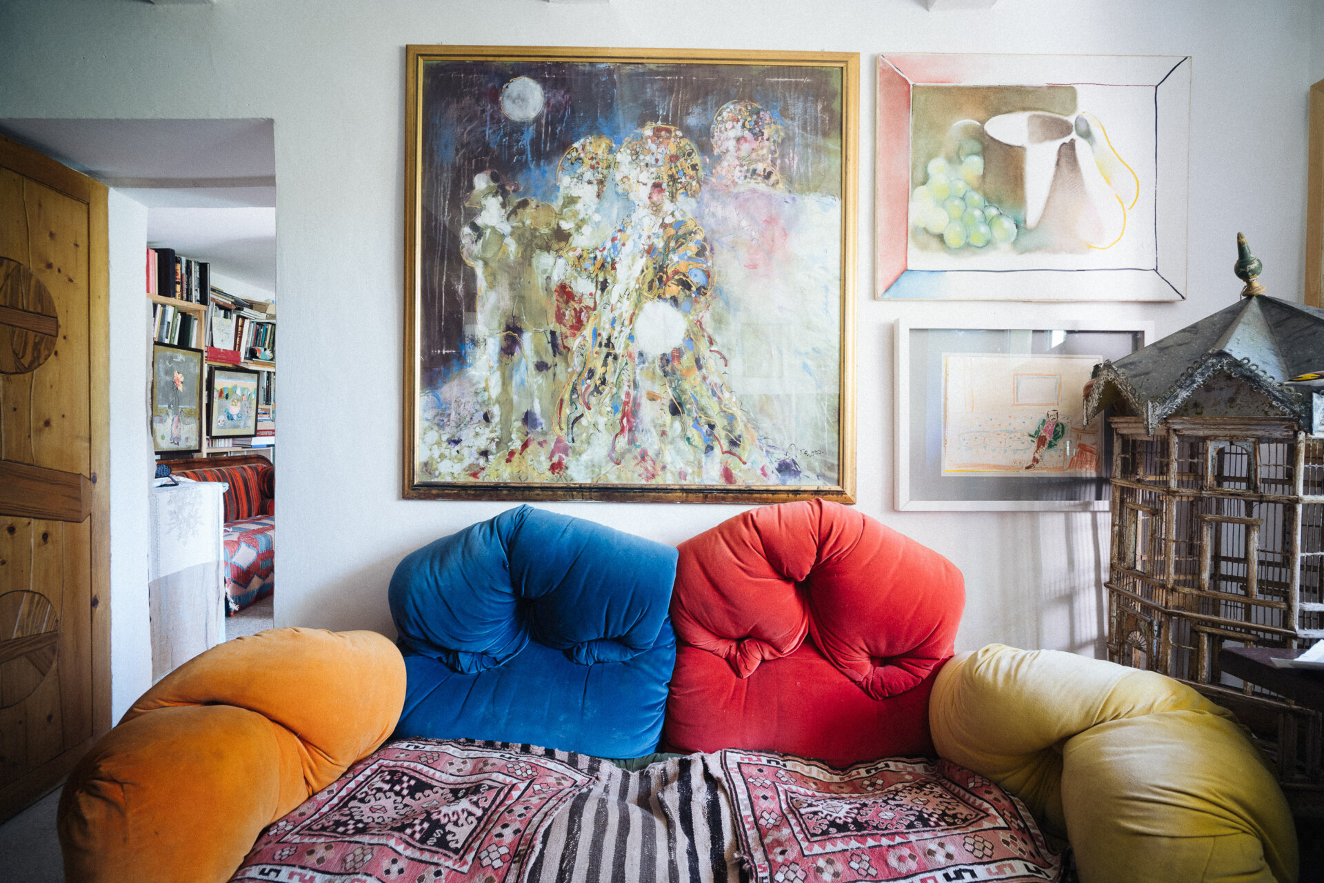 brightly colored couch cushions with cluttered wall decor in tonino guerras house