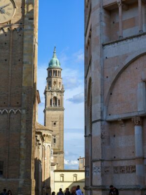 an image of a a tall bell tower between roofs and buildings in Parma