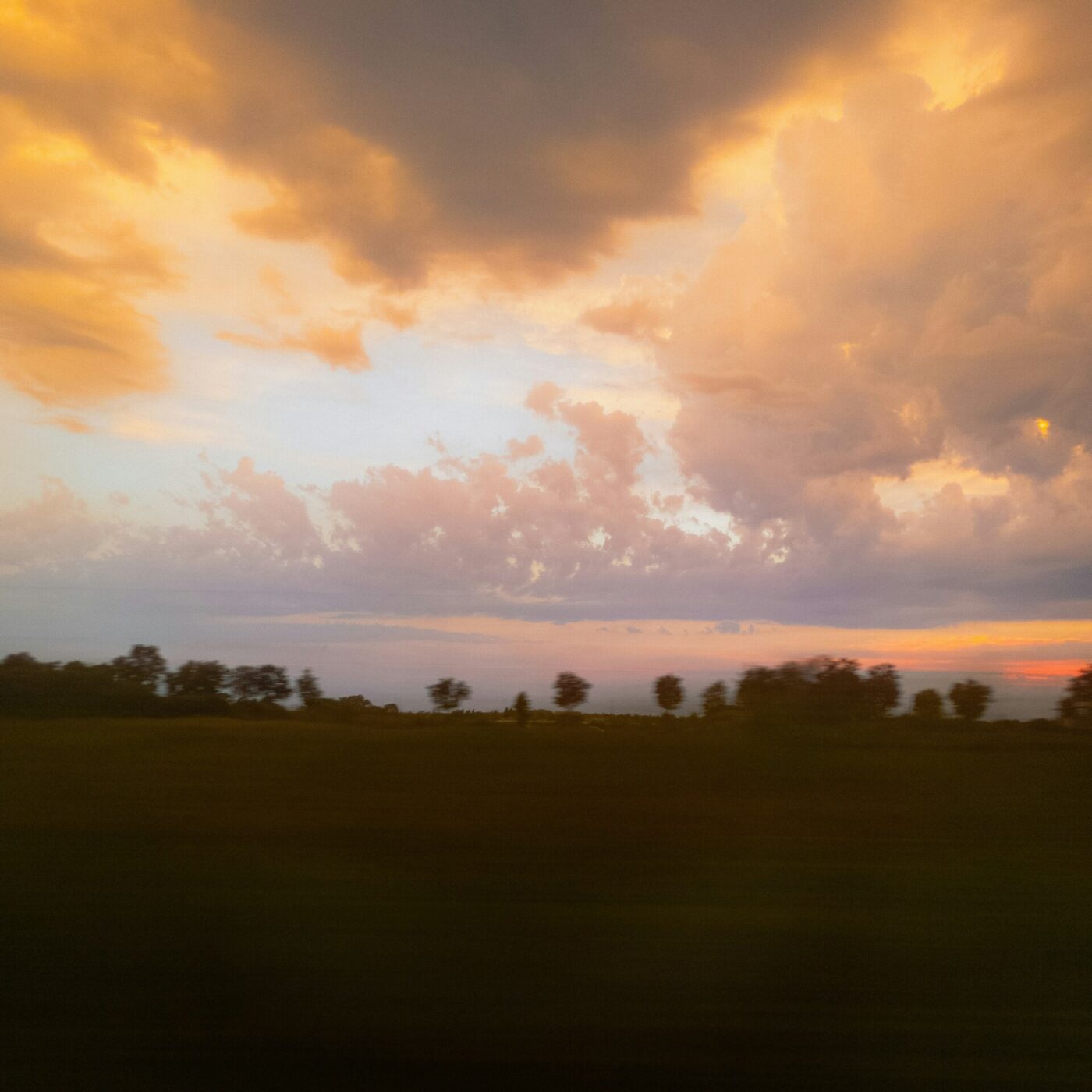 a pink sunset over darkened countryside hills