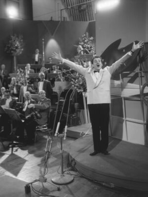 a black and white image of Domenico Modugno singing with his arms raised