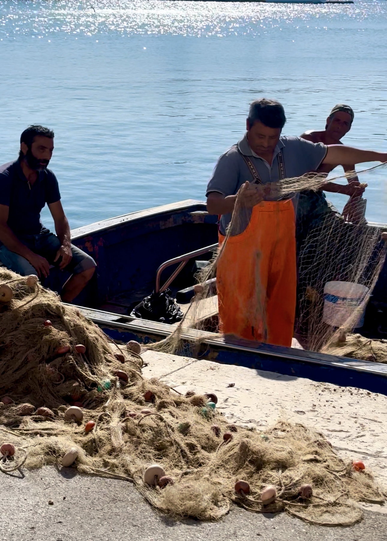 an image of three fishermen on a boat in Puglia looking through their nets