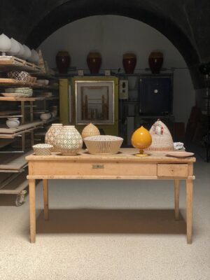 A variety of ceramics sitting on a wooden desk in a sort of storage room in Puglia