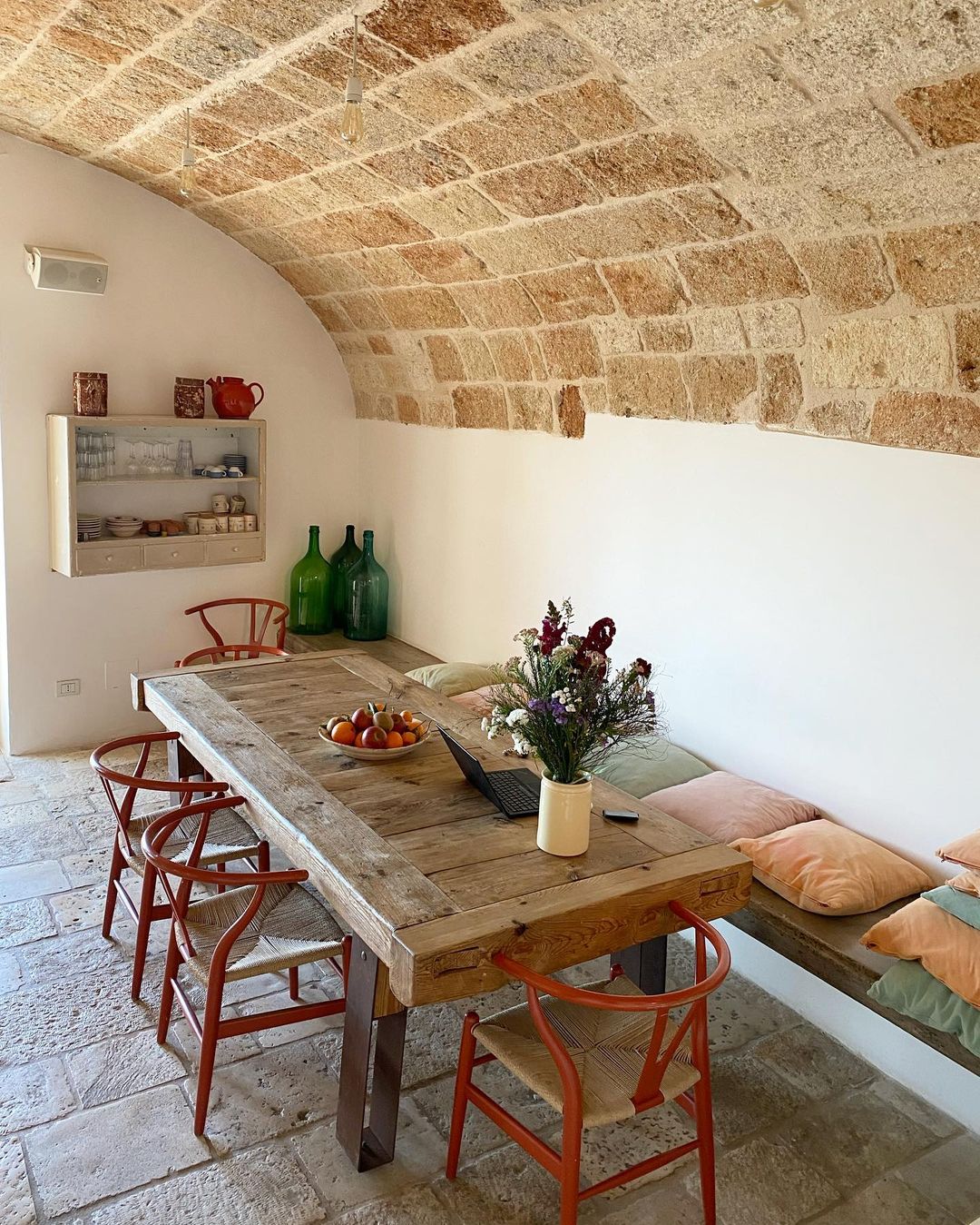 the wooden dining room table at Palazzo Penelope underneath a curved roof and with a cushion-covered bench on one side