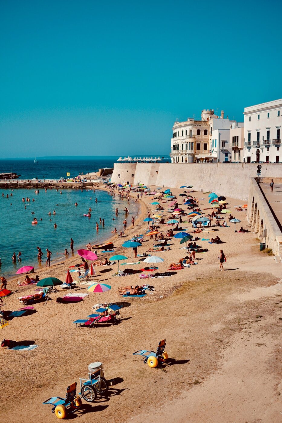 a sandy beach lined with umbrellas at Gallipoli in front of the walled town
