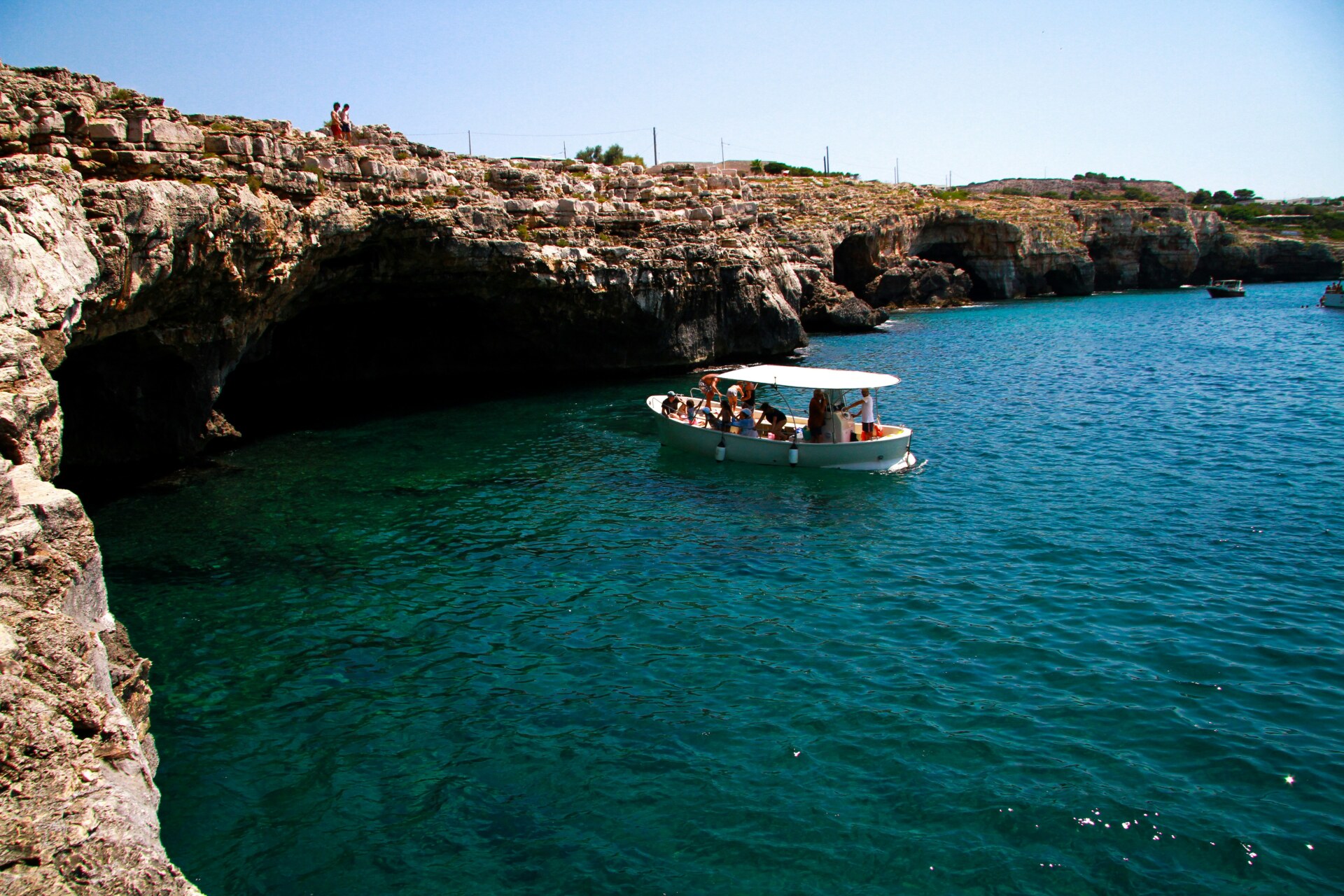 a boat pulling up to a small cave in Santa Maria di Leuca