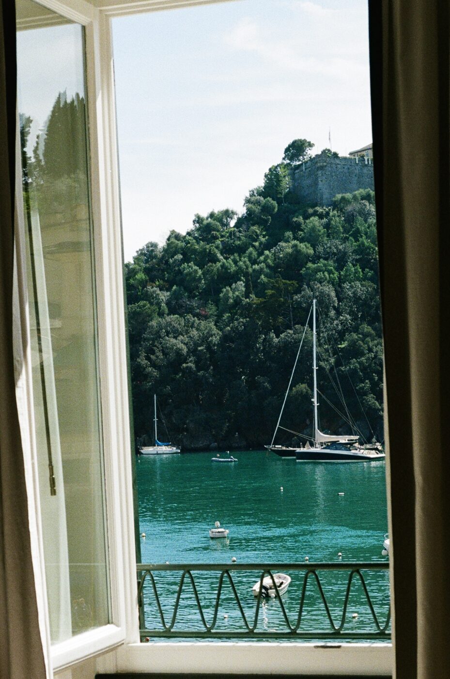 an image through a window of the blue sea with sailboats in portofino