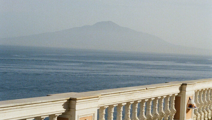 an image of a balcony with bright colored tile floors looking towards the ocean and Vesuvius