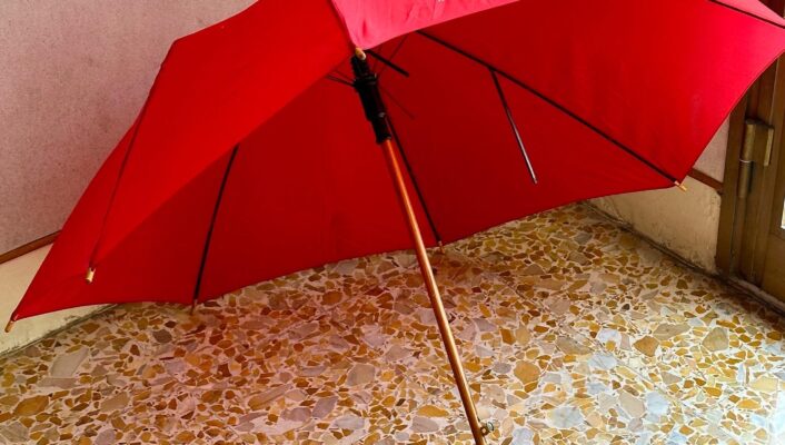 an image of a bright red umbrella open and lying on the ground