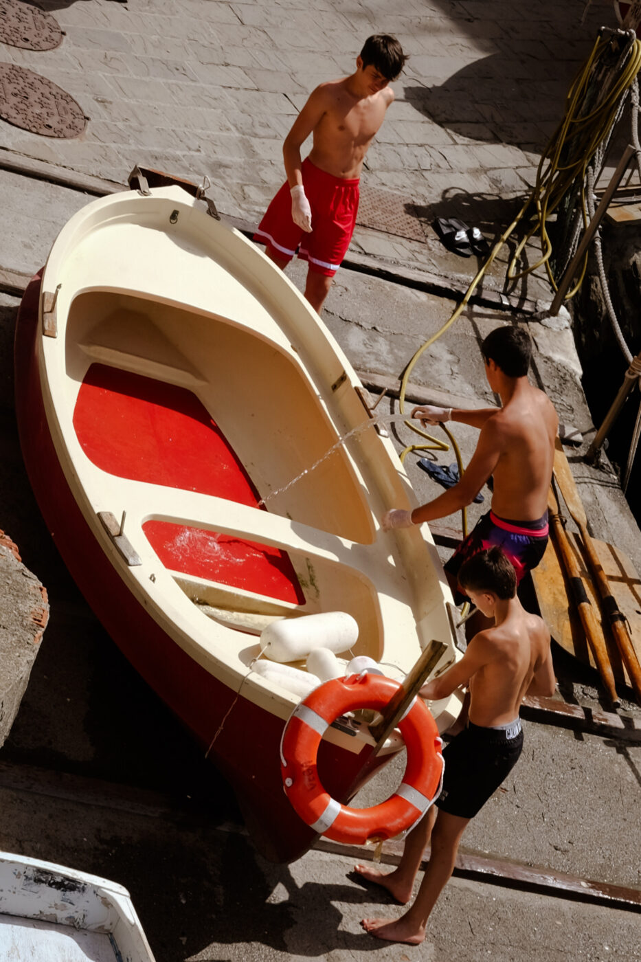an image of three young boys cleaning their boat with clear water
