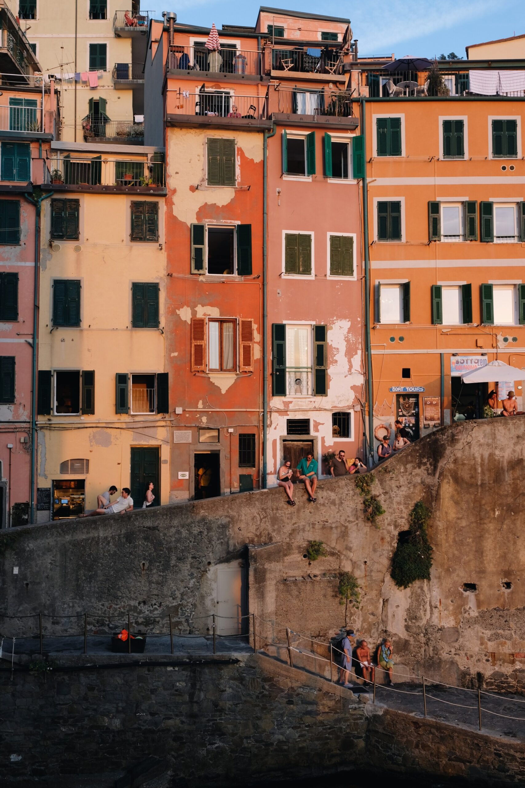 a shaded image of Riomaggiore with people sitting along the wall