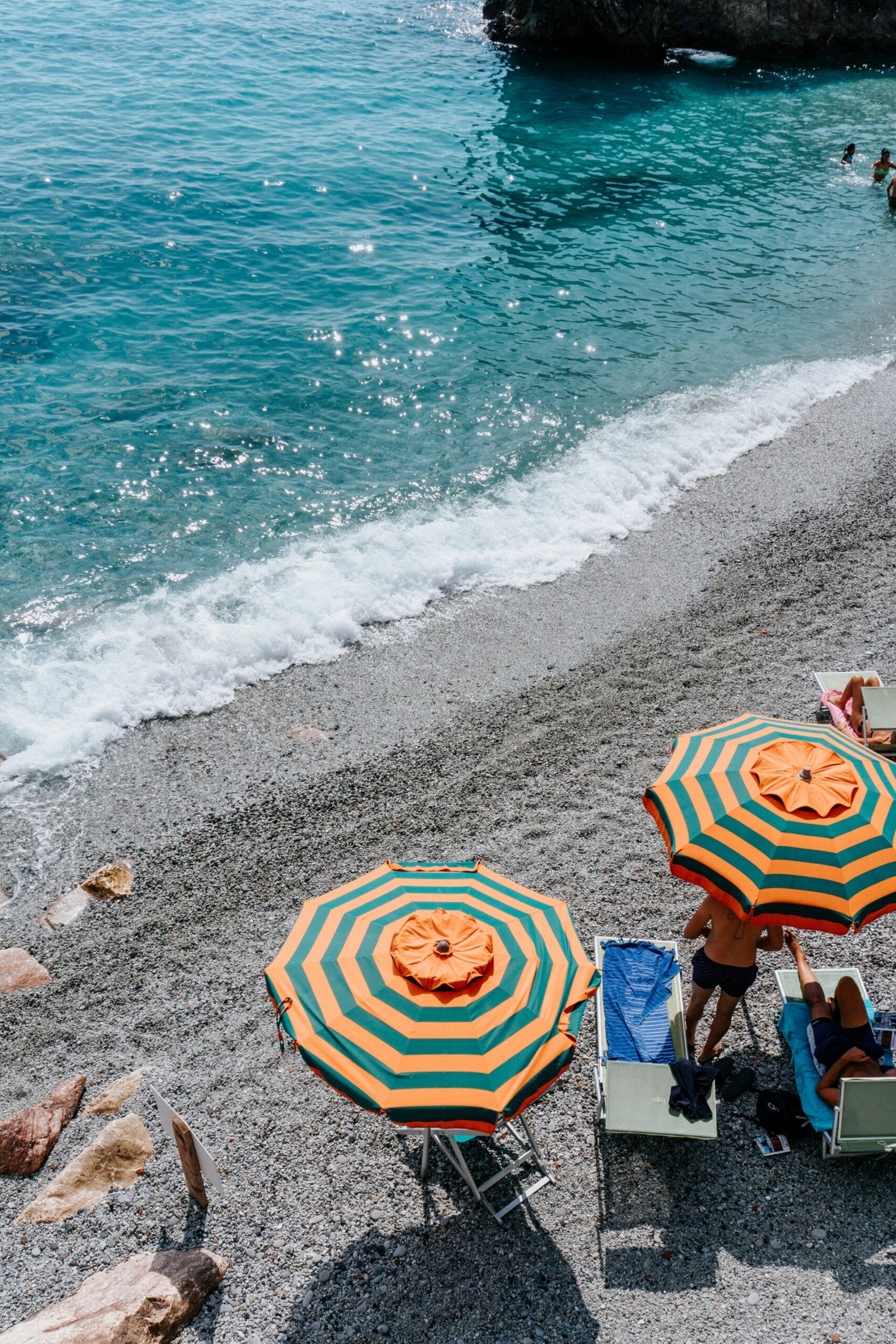 an image of the Stella Marina Beach Club with orange and blue stripped umbrellas in the sand along the water