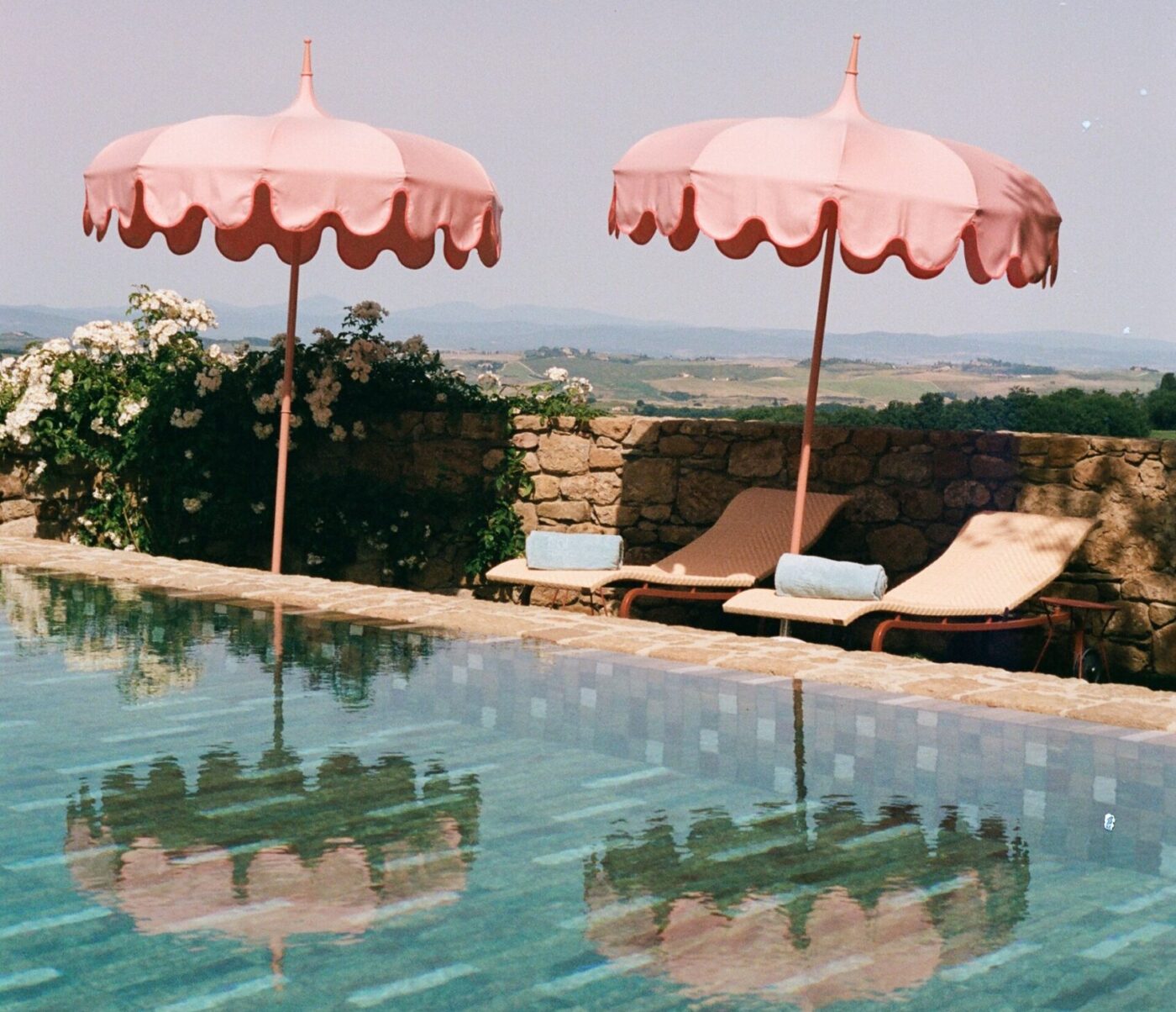 the pool at Casa Newton with pink umbrellas reflecting into the water and lounge chairs with towels rolled up