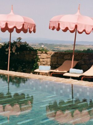 the pool at Casa Newton with pink umbrellas reflecting into the water and lounge chairs with towels rolled up