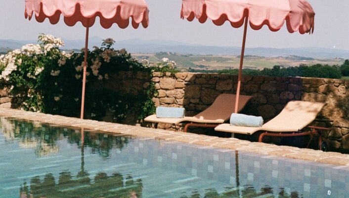 the pool at Casa Newton with pink umbrellas reflecting into the water and lounge chairs with towels rolled up
