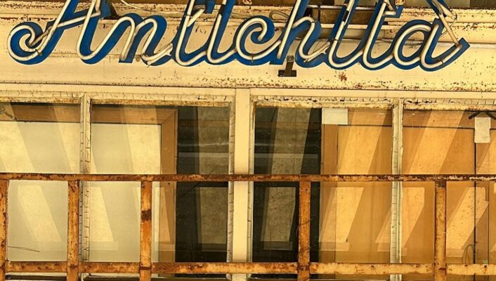 a storefront with the sign antichitta in cursive neon lettering