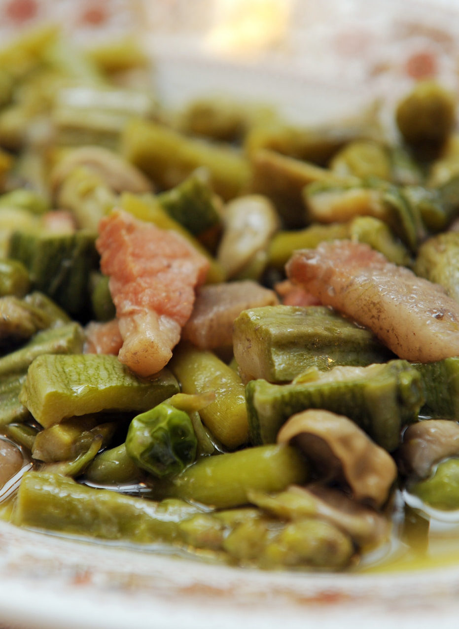 a close up of vignarola, a spring warm salad with green veggies and guanciale