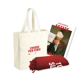 Estate Italiana Red Bundle - The Estate Italiana Red Bundle features a white tote bag with red text, a rolled-up red towel, and a magazine showing a hand holding an ice cream cone, all arranged against a white background.