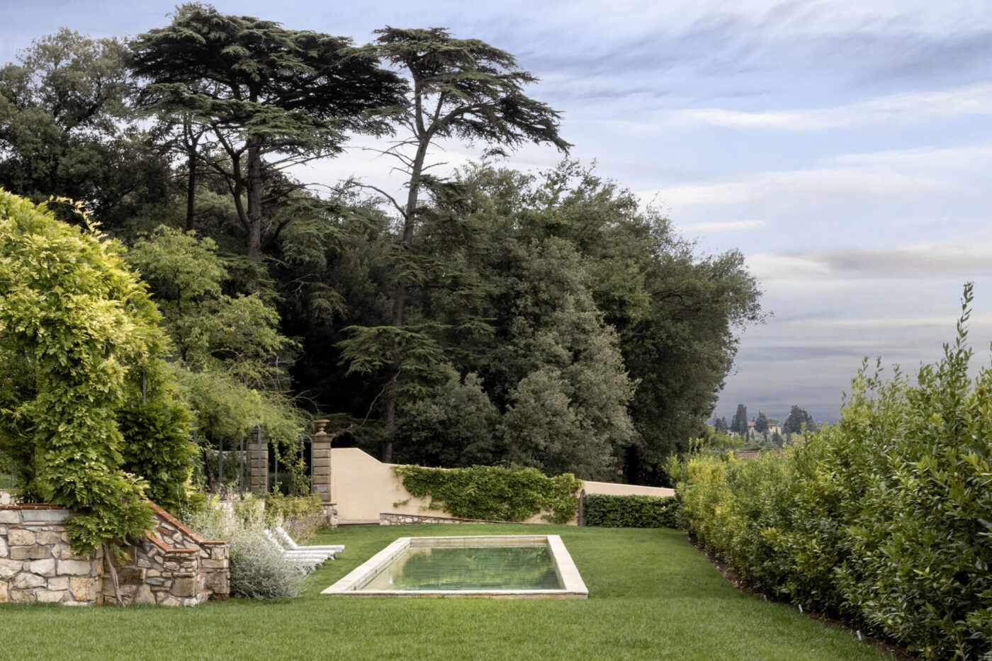 the sunken in pool at La Chiocciola with grass and a beautiful forest behind