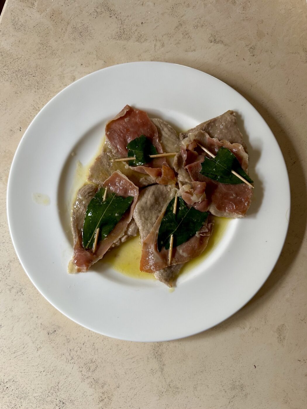 four pieces of saltimbocca alla romana, thin veal with prosciutto and sage held together with a toothpick