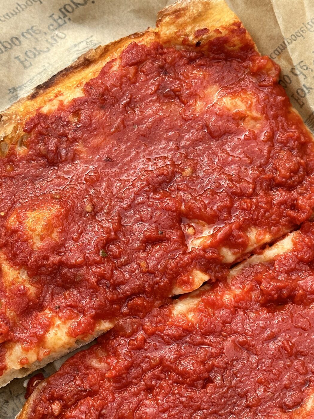 a piece of pizza rossa with bright red tomato sauce on it