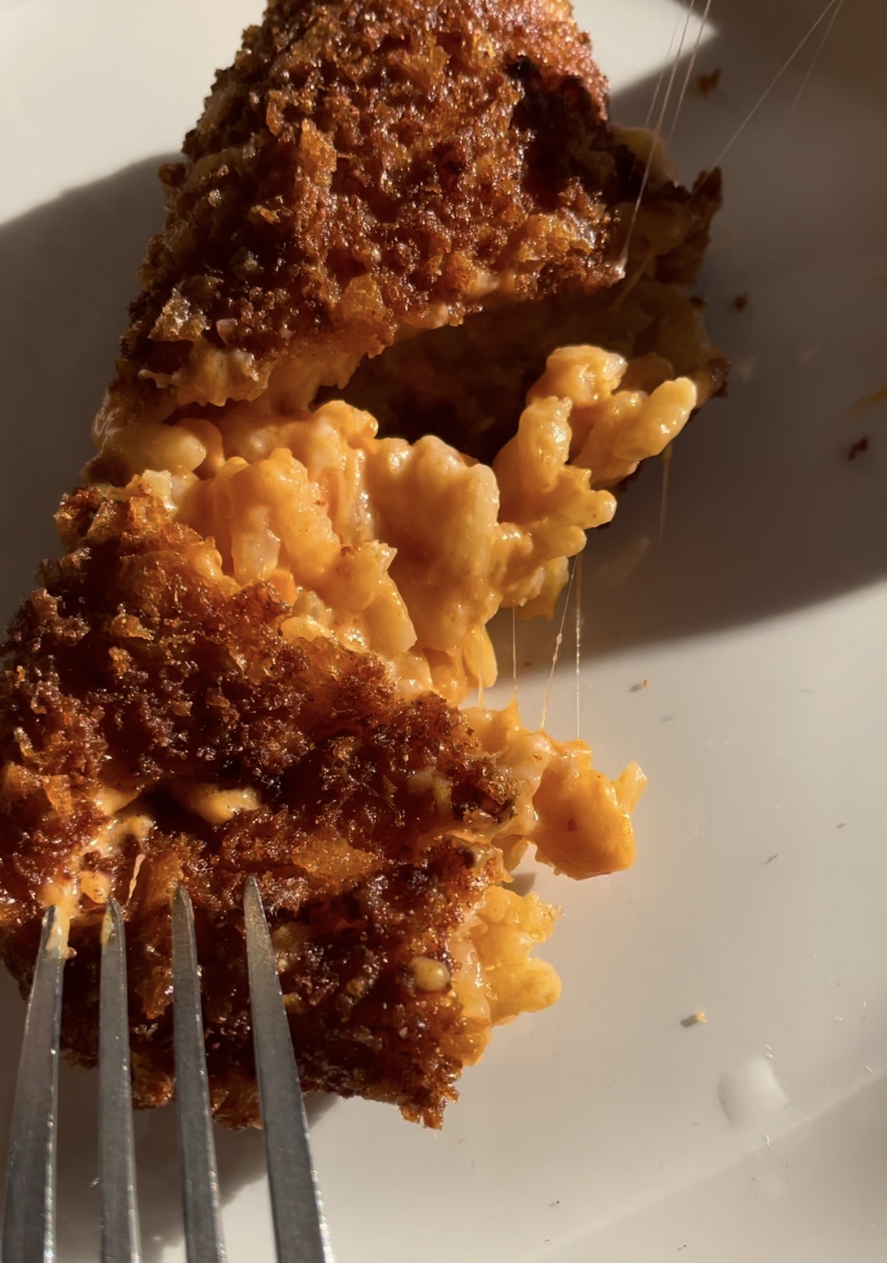 an image of a fork breaking into a gooey crispy suppli (rice ball)