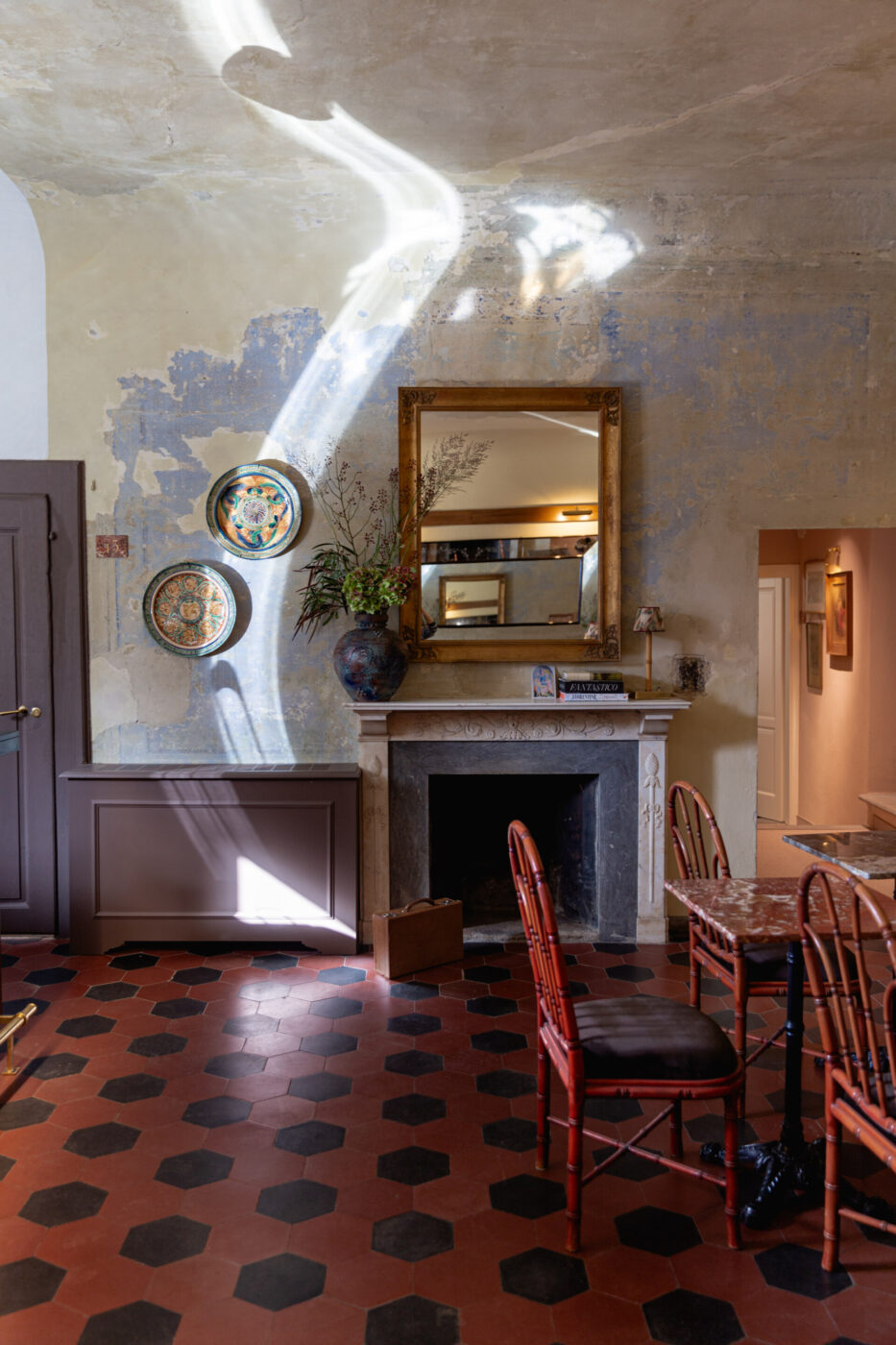 an image of the interior of stella d'italia with a fireplace, tables and chairs, and fun wall decor on a marbled wall