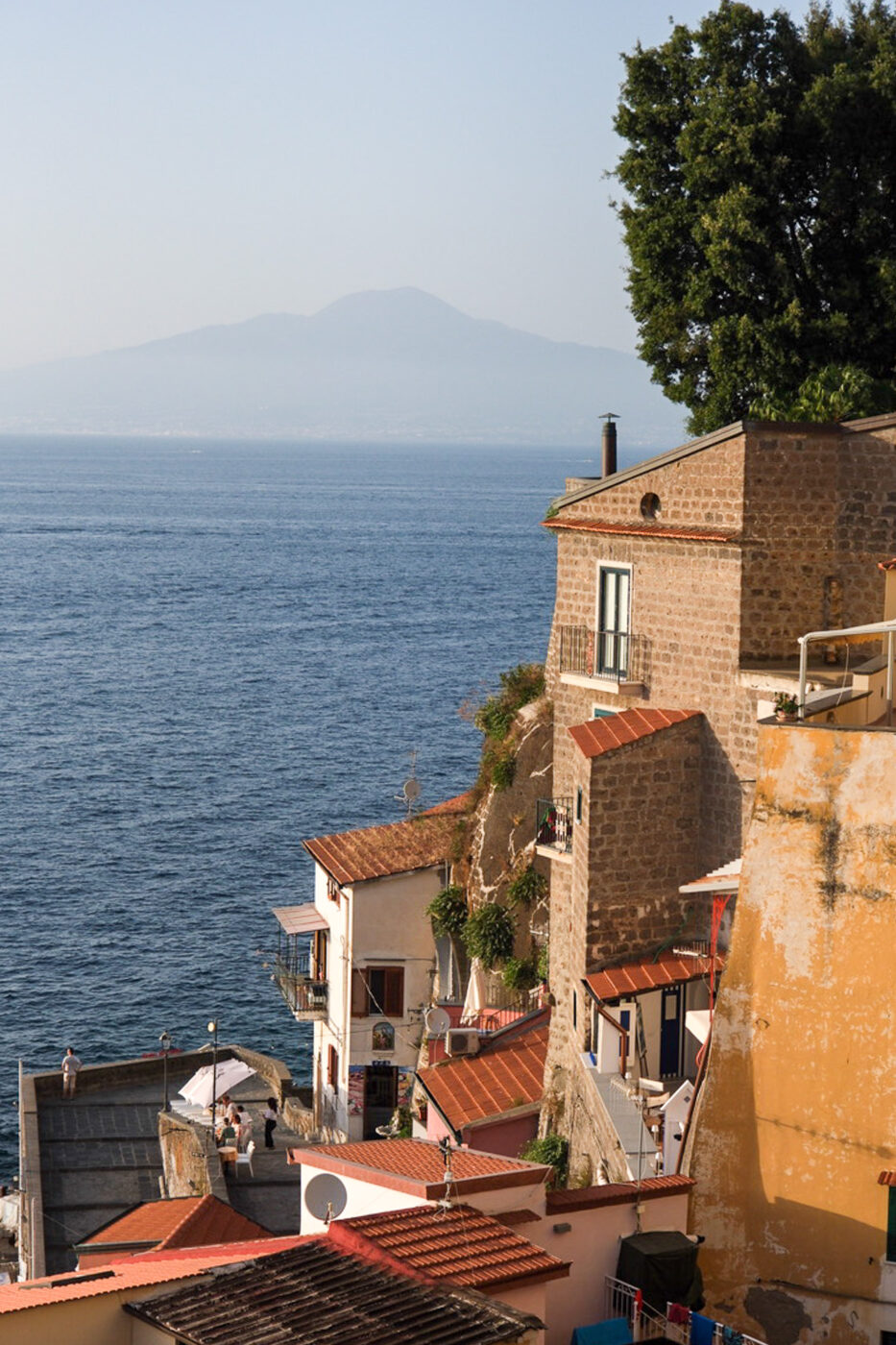 the marina grande in sorrento with houses cascading down into the sea in front of Vesuvius