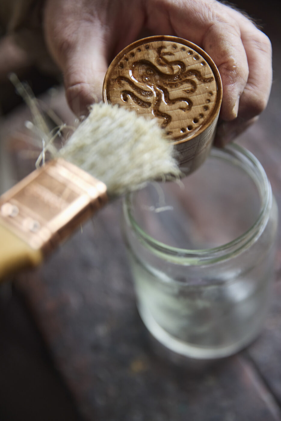painting a sealant onto a wooden stamp in the shape of an octopus to stamp our cortzetti pasta