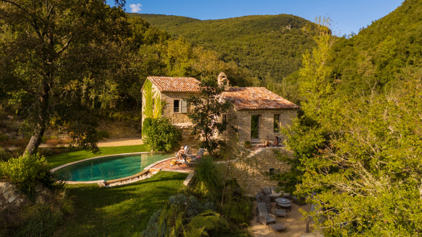 an image of tenuta di murlo with the turquoise pool in front of the ivy covered two story stone villa