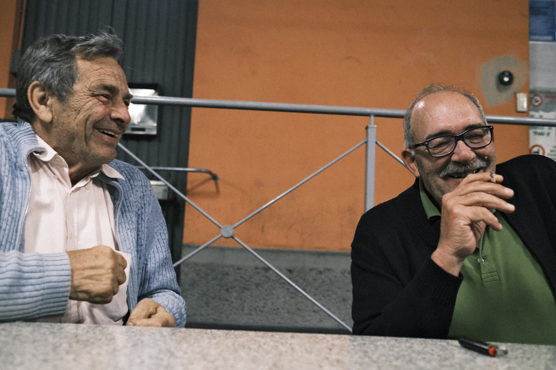 two men laughing and sitting outside the cooperative