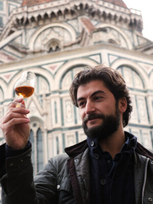 a man holding a glass of whiskey and admiring it in front of the duomo in Florence