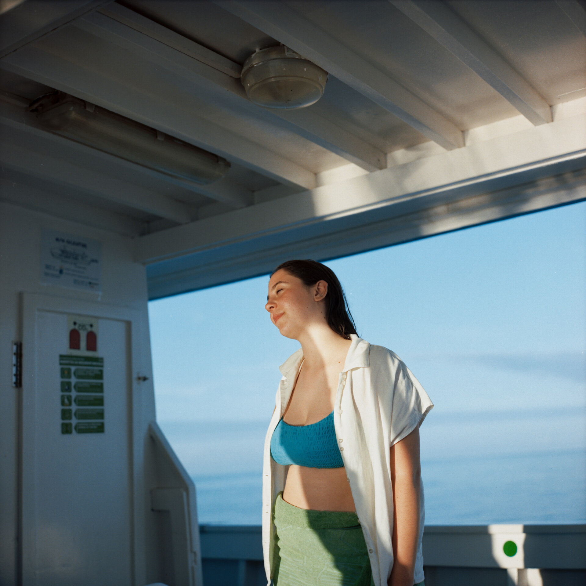 an image of a teen on a ferry smiling as the sun rays hit her face