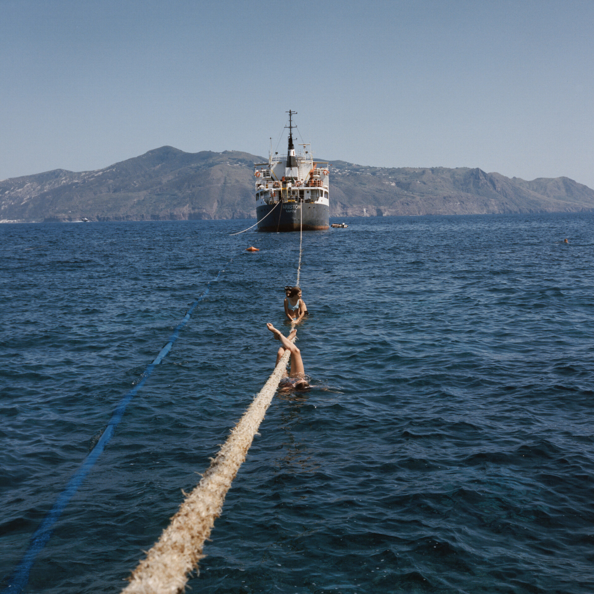 an image of teens hanging off of the rope of a ferry