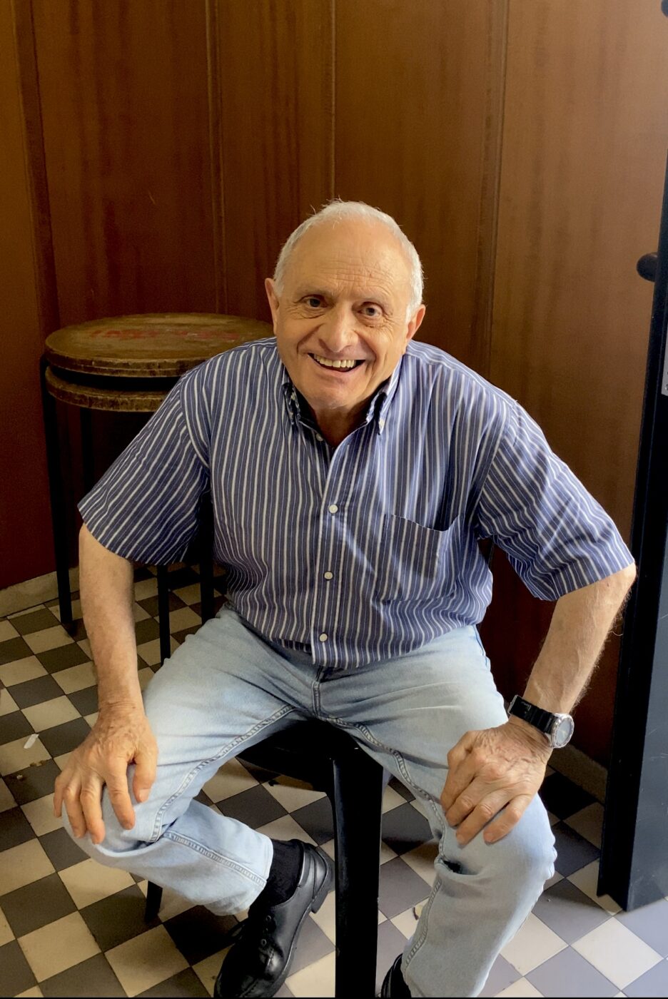 a cute old man sitting with his hands on his knees