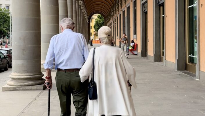 an elderly couple walking away under a covered walkway
