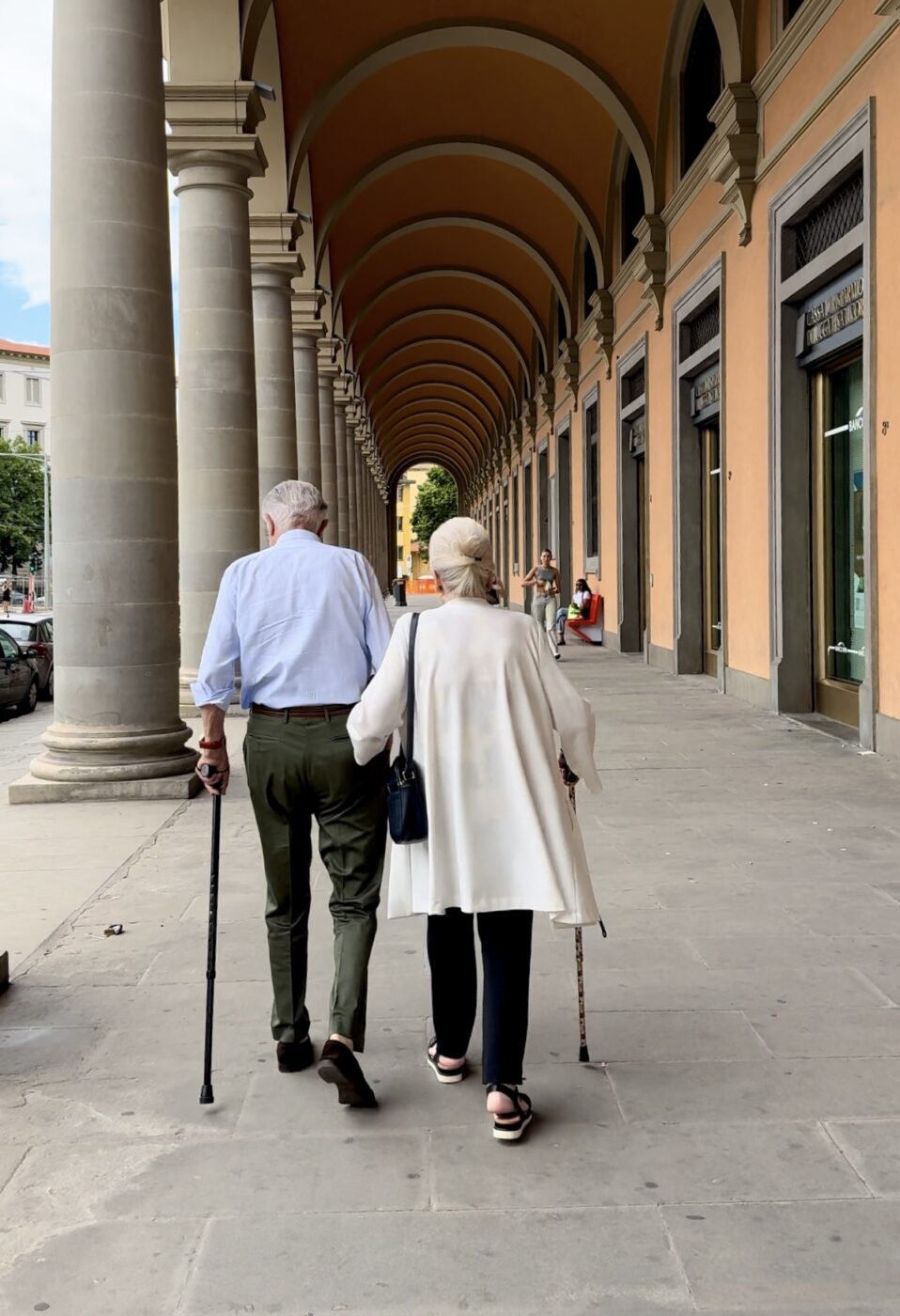an elderly couple walking away under a covered walkway