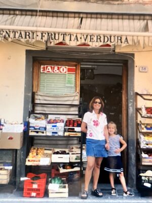 a vintage image of a mom and her daughter in front of an alimentari