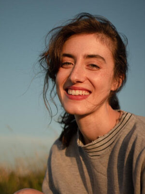 an image of a young girl smiling with her hair in a pony tail slightly blowing in the wind