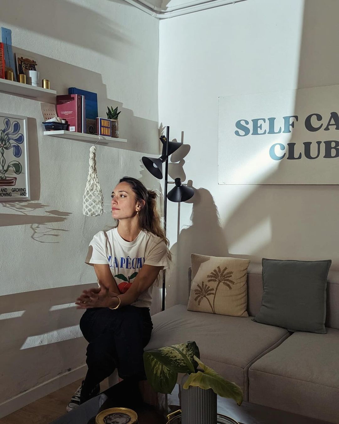 a woman photographed sitting on a couch in a t shirt with long blond hair slightly pulled back