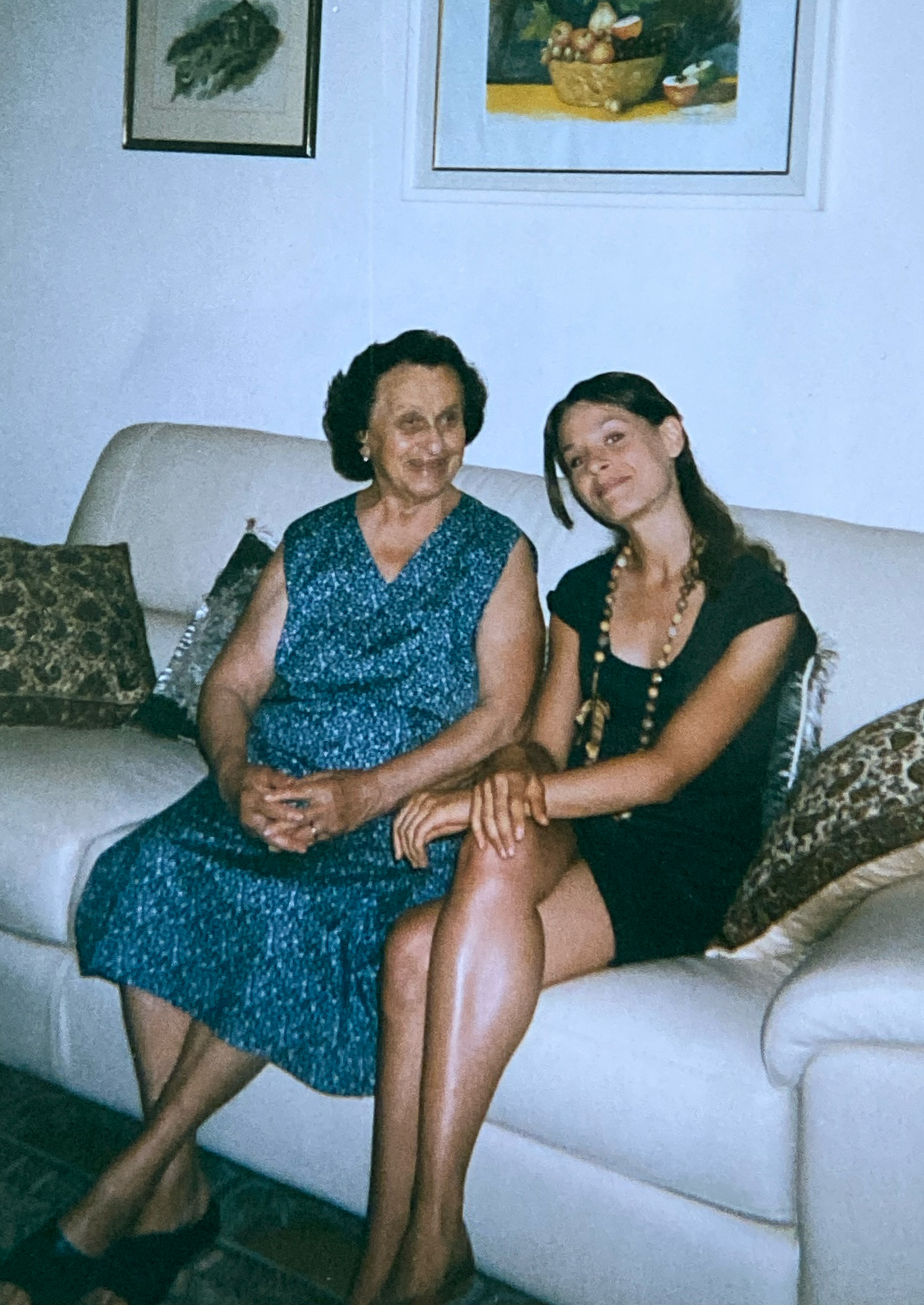 a vintage image of a young girl sitting with her grandmother on a white couch