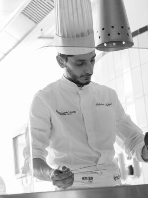 A black and white photo of a chef with fish tongs