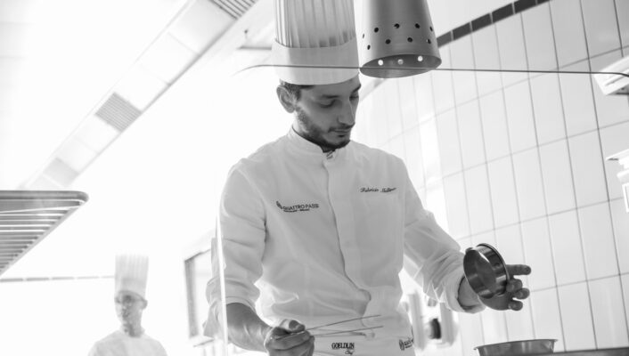 A black and white photo of a chef with fish tongs