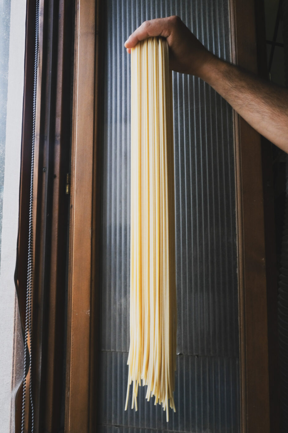 someone holding long strands of drying tirrena spaghetti