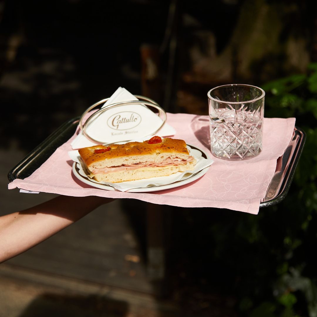 a waiter carrying a silver tray at Gattullo with stuffed focaccia and napkins
