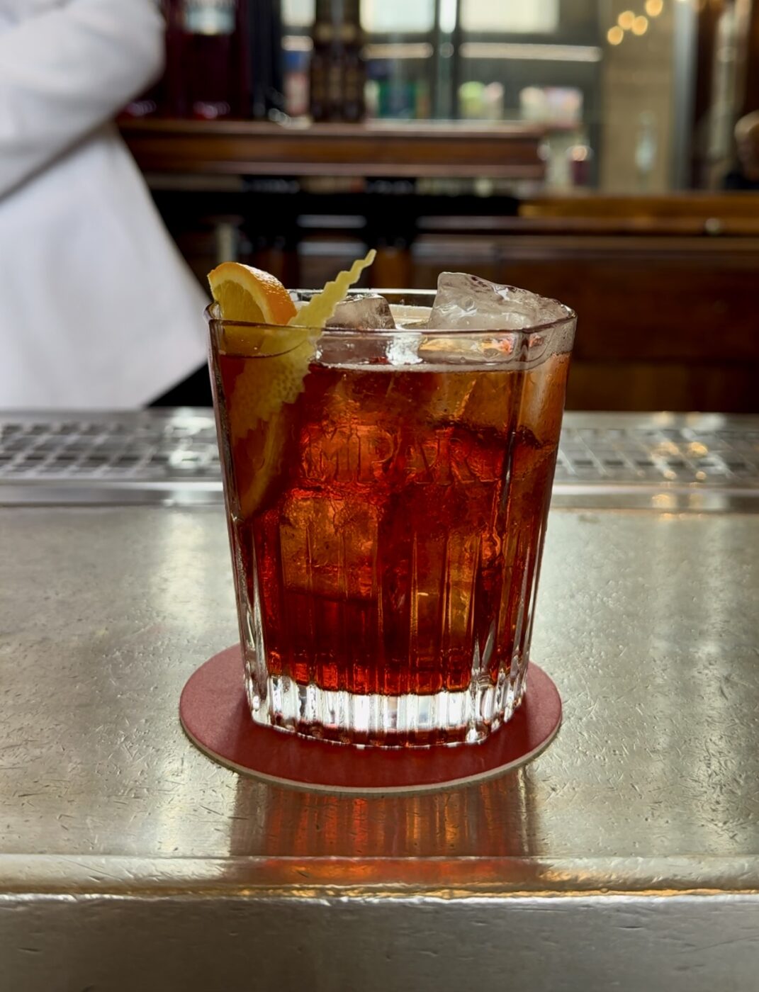 a bar counter with a glass of a milano-torino cocktail in milan